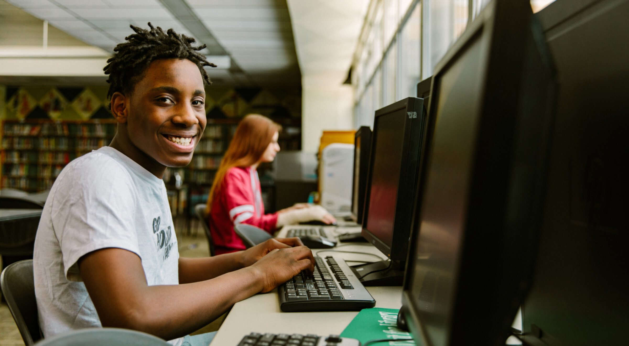 Boy smiling at computer in library