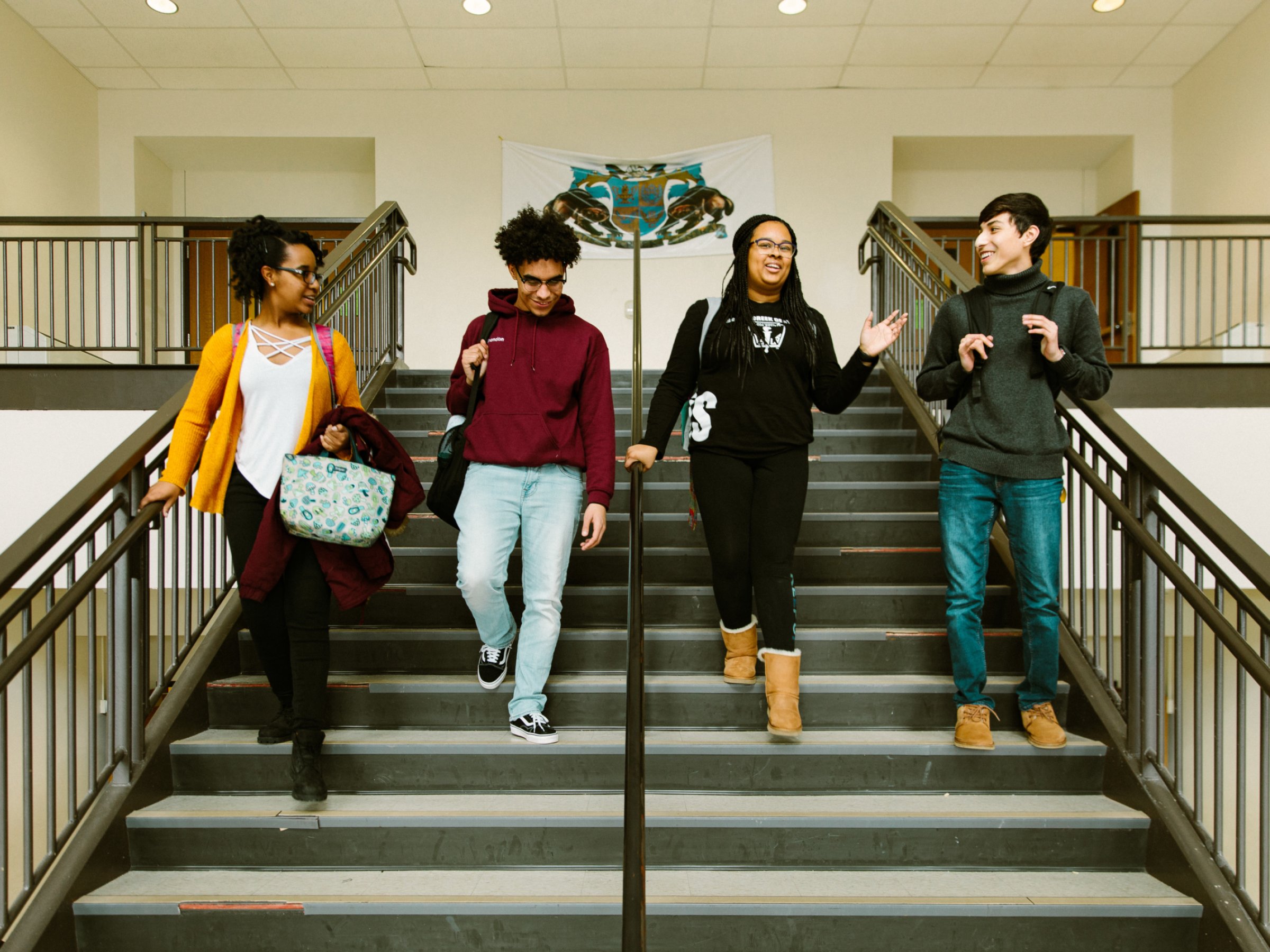 Four students talking while walking down stairs