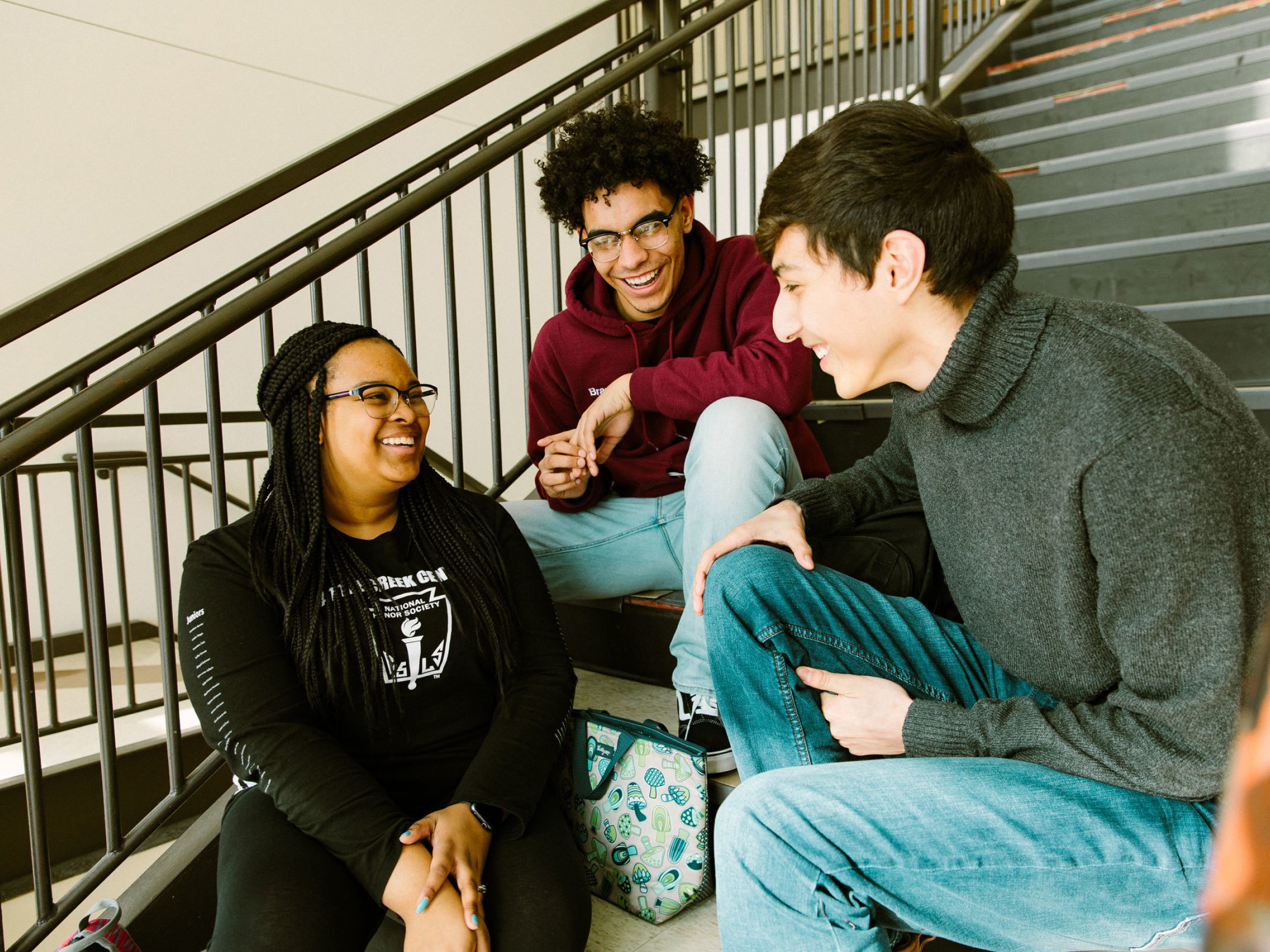 Three students engaged in conversation sitting on a stairwell