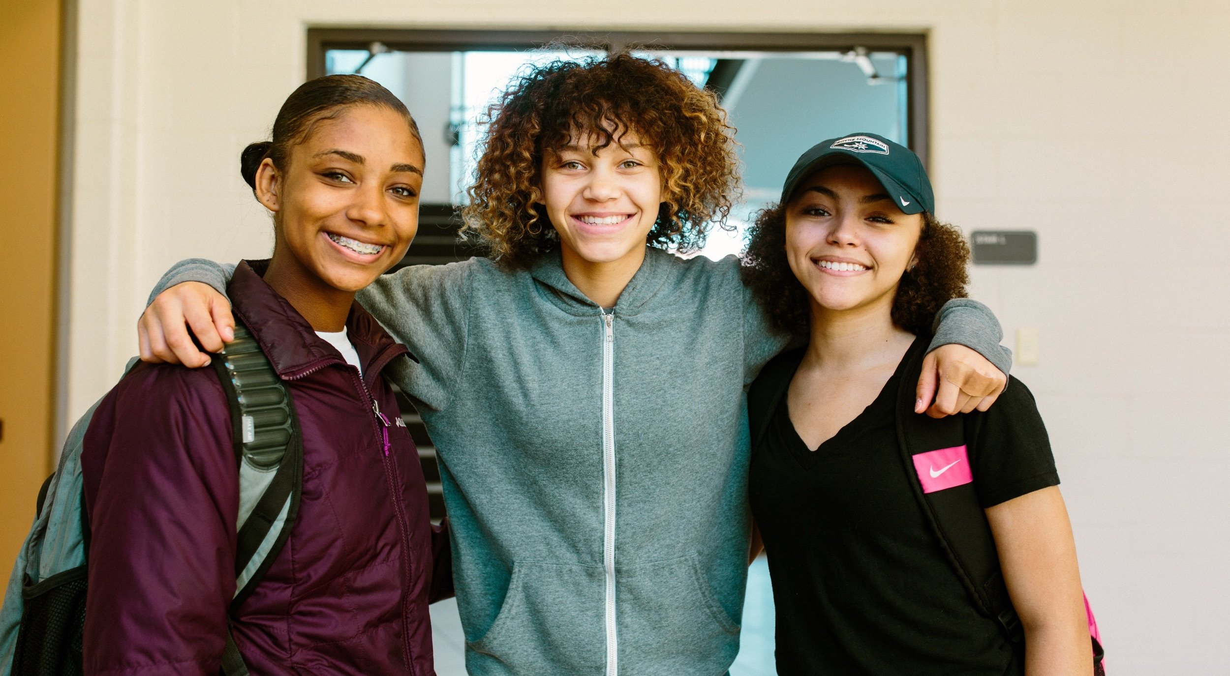 Three students stand together smiling