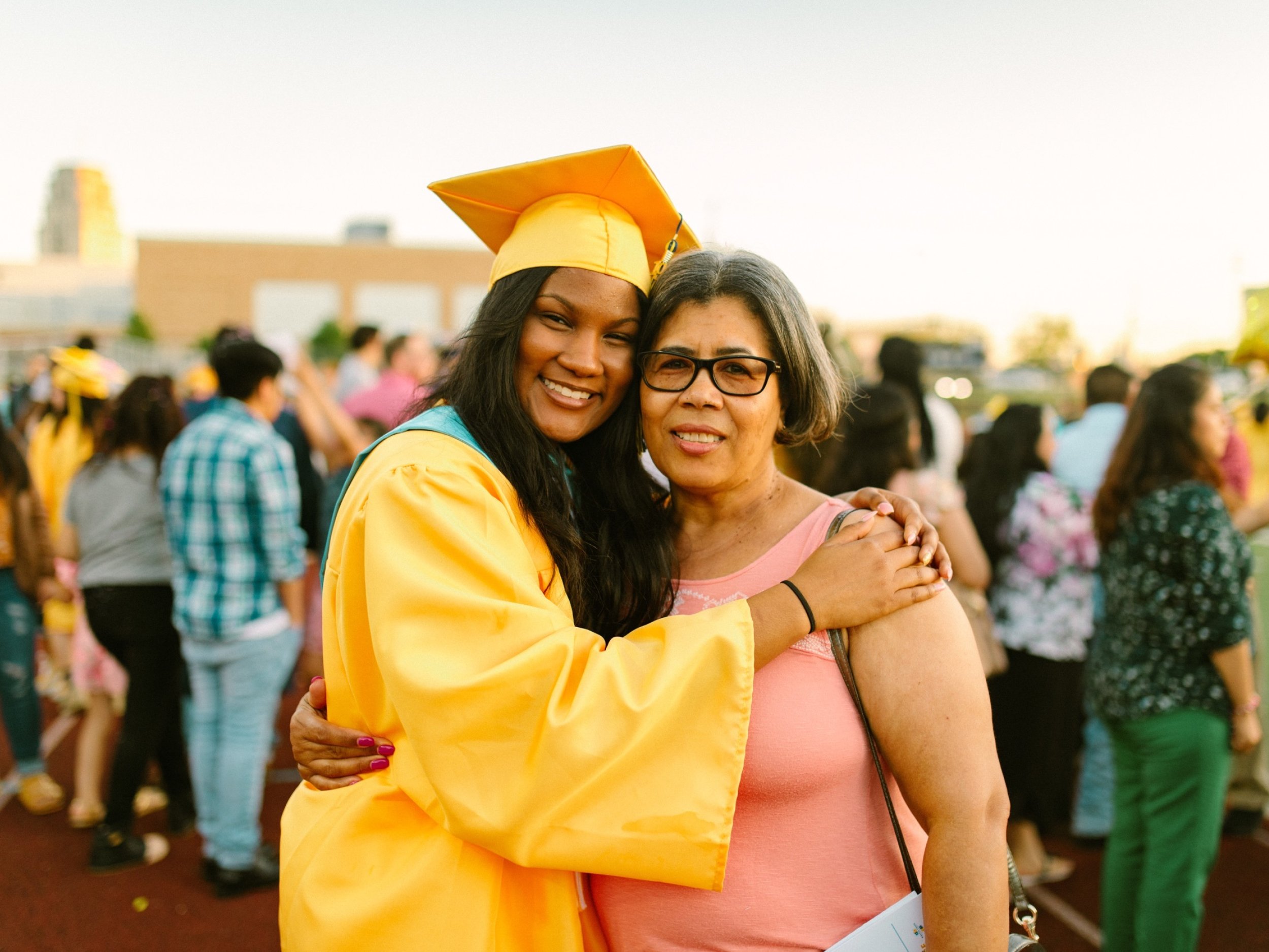 A graduating senior in cap and gown hugs a parent at the ceremony