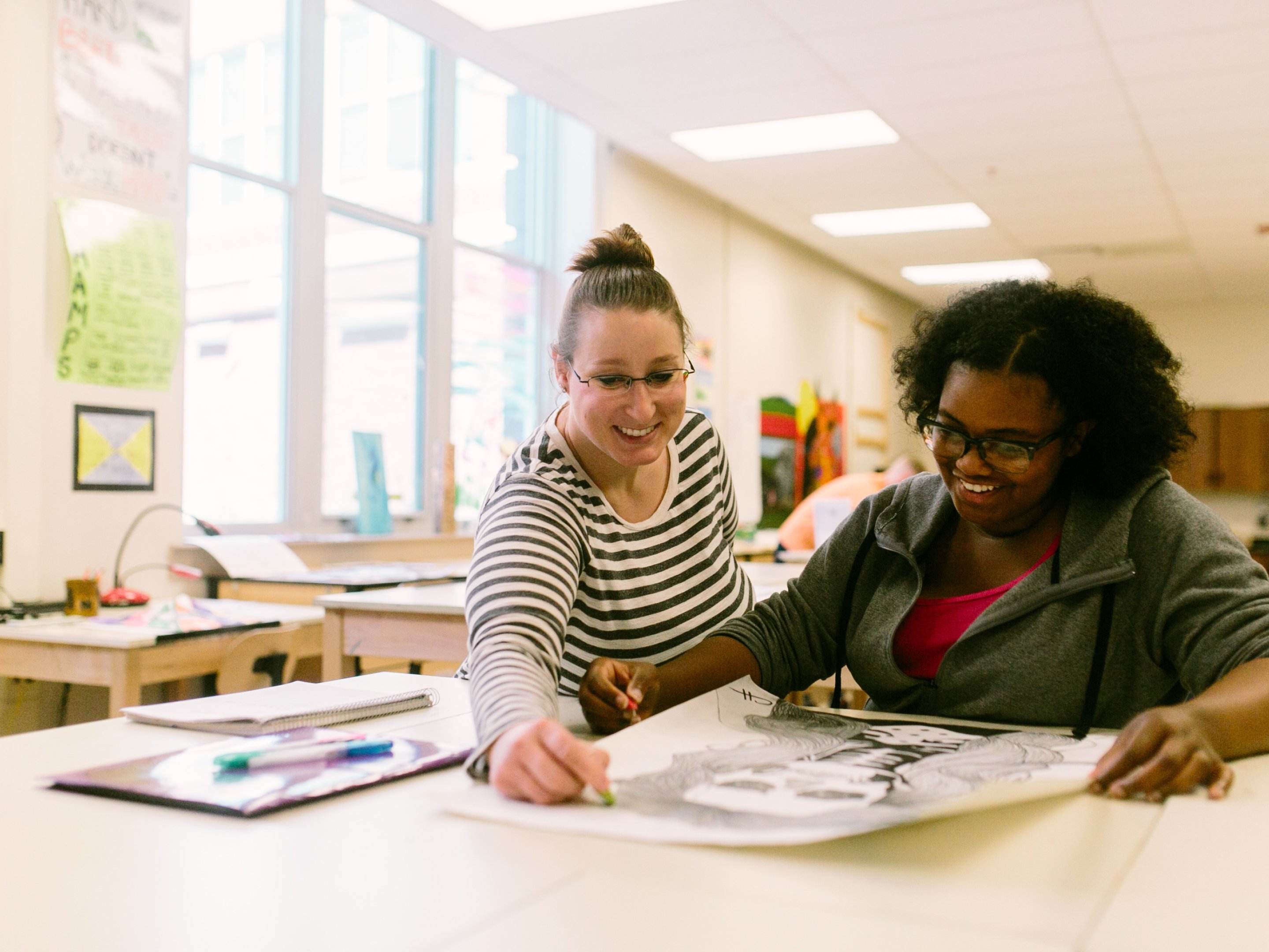 An art teacher helps a student with their drawing in art class